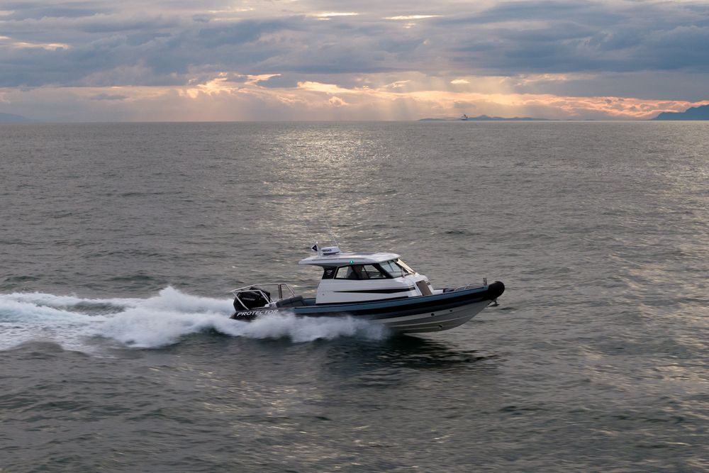 Protector Targa running through open coastal water with mountains behind