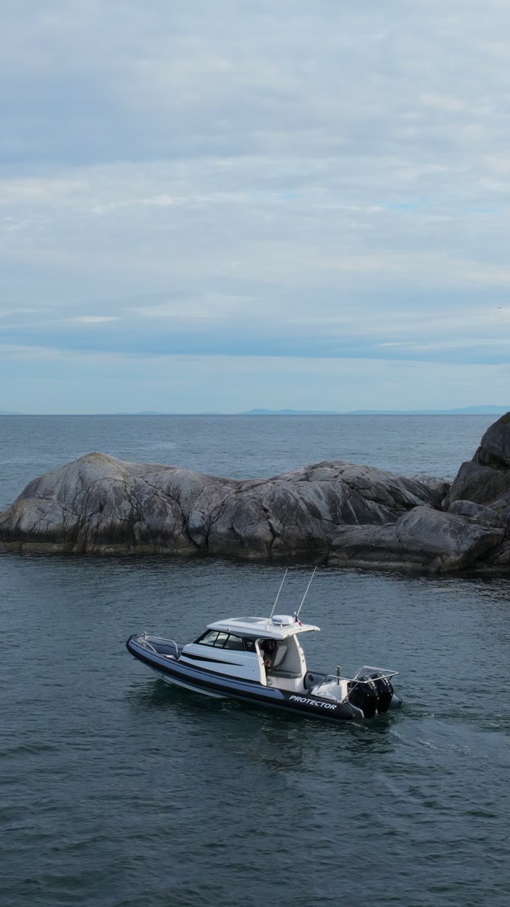 Protector Targa running past a rocky islet on the British Columbia coast